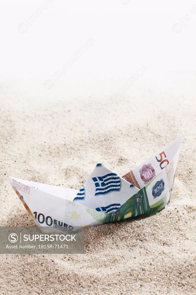 Origami paper boat of euro notes on sand