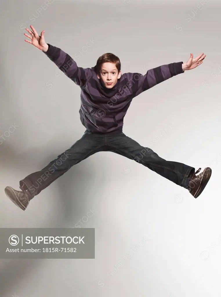 Boy 12_13 jumping against gray background
