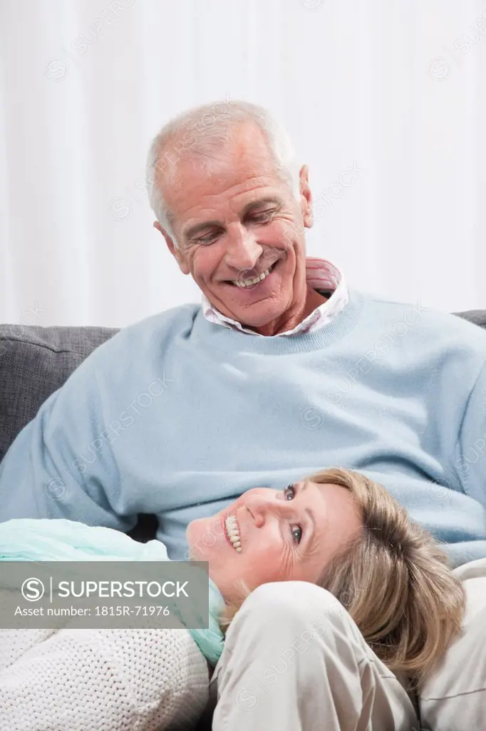 Man sitting with woman lying on lap, smiling