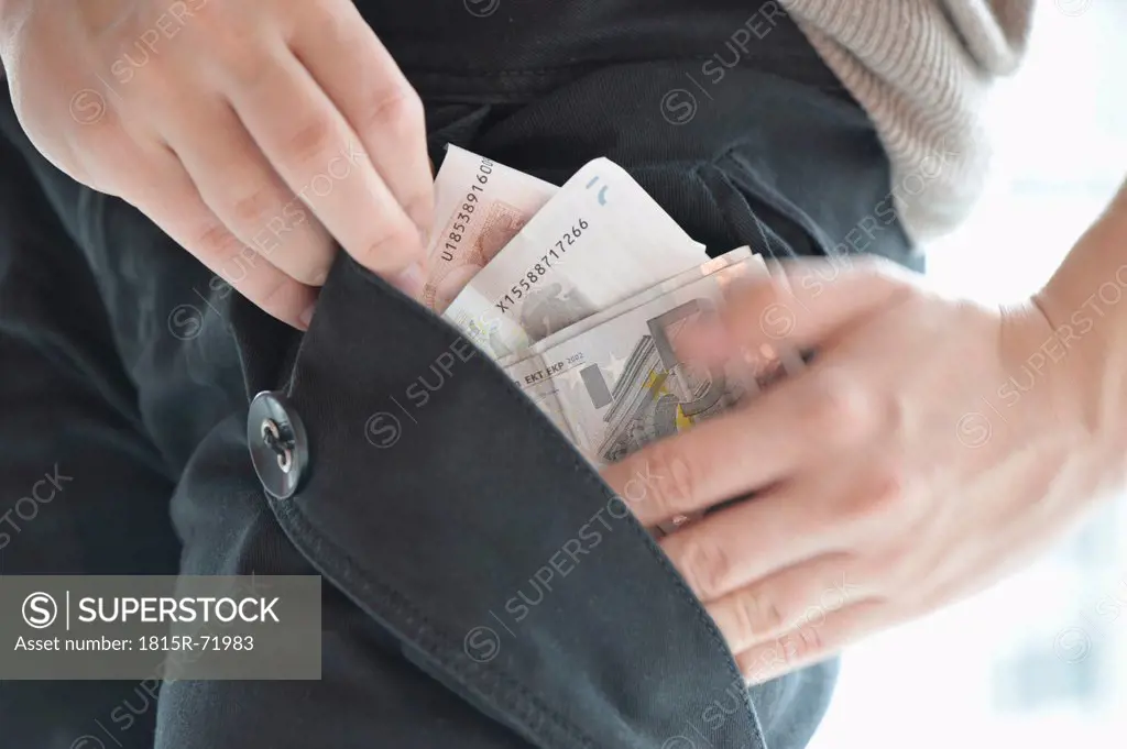 Woman putting euro bills in pocket, close up.