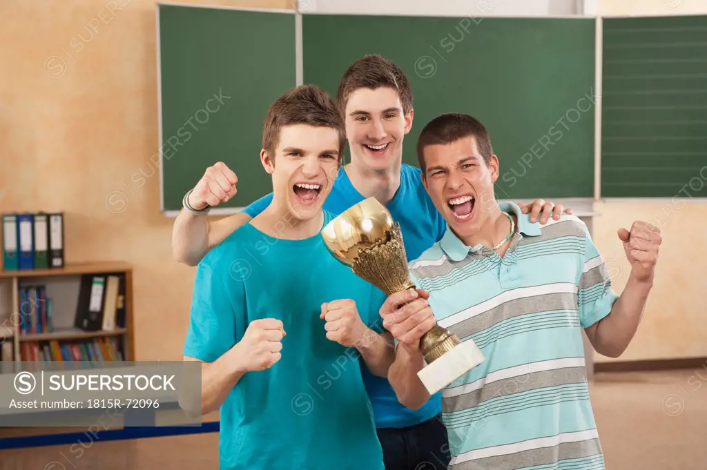 Germany, Emmering, Friends holding trophy and clenching fist, smiling