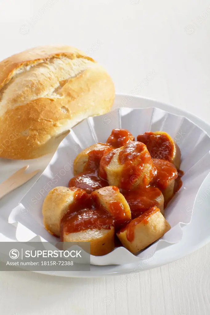 Curry sausage with bread roll in plate on white background