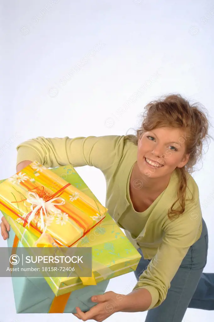 Young woman holding gift packages, smiling, portrait