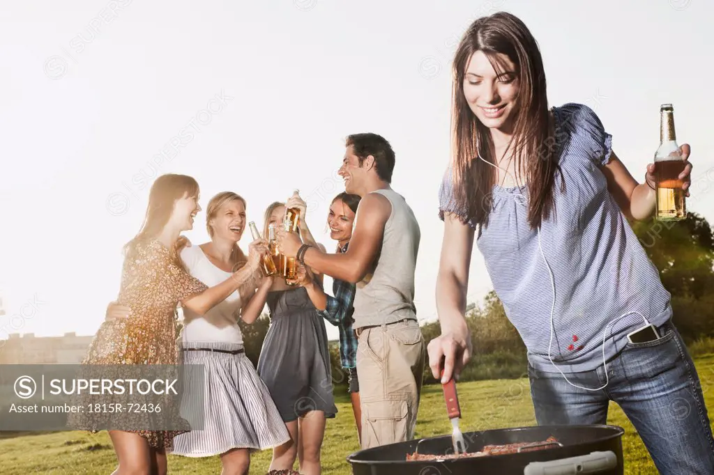 Germany, Cologne, Woman barbecueing with friends in background