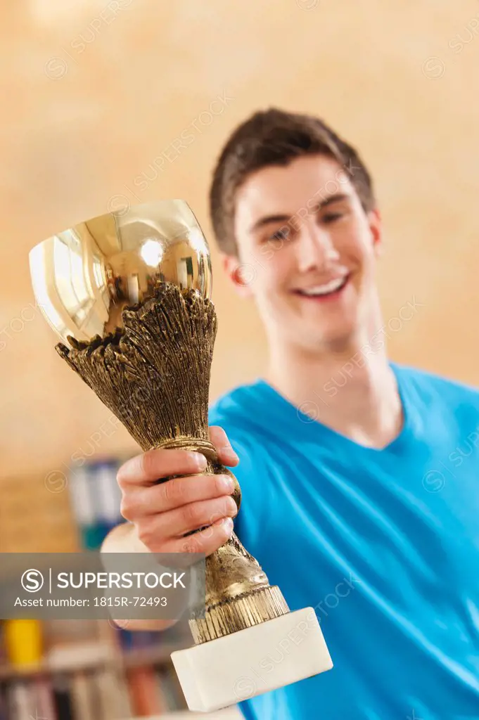 Germany, Emmering, Teenage boy holding trophy, smiling, portrait
