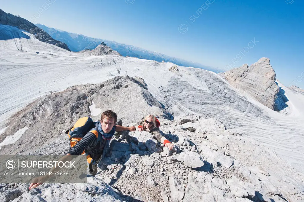 Austria, Steiermark, Dachstein, Young couple climbing rock