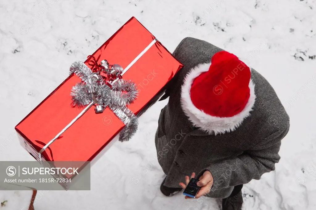 Germany, Cologne, Man with christmas present and using mobile