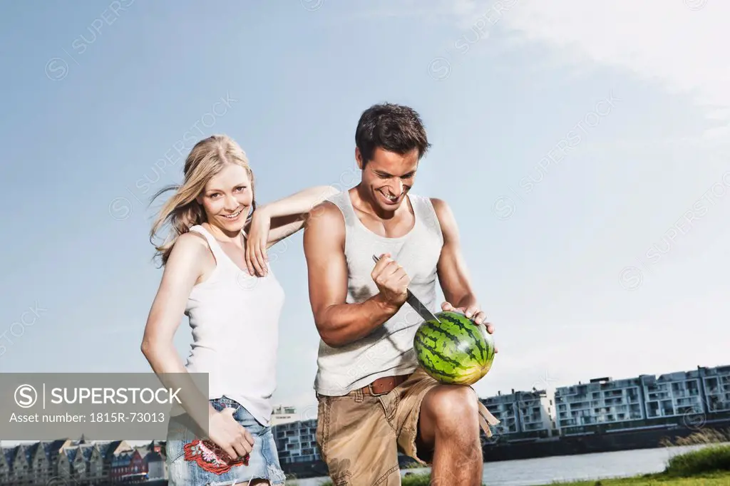 Germany, Cologne, Man cutting watermelon, woman smiling