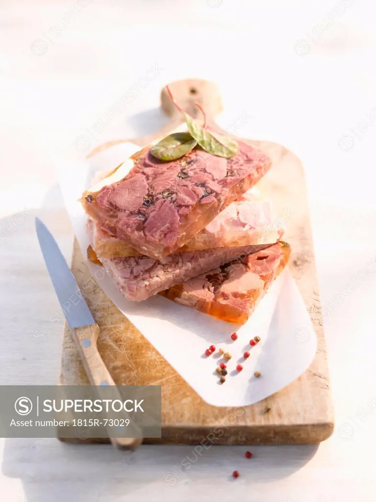 Pork in aspic on wooden board with knife