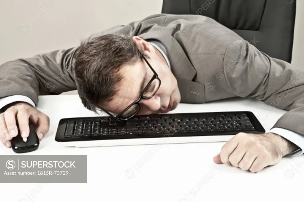 Close up of mature businessman lying on keyboard at office