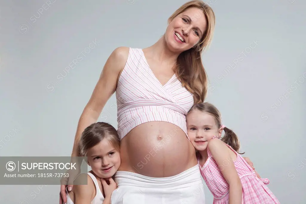 Daughters with pregnant mother, smiling