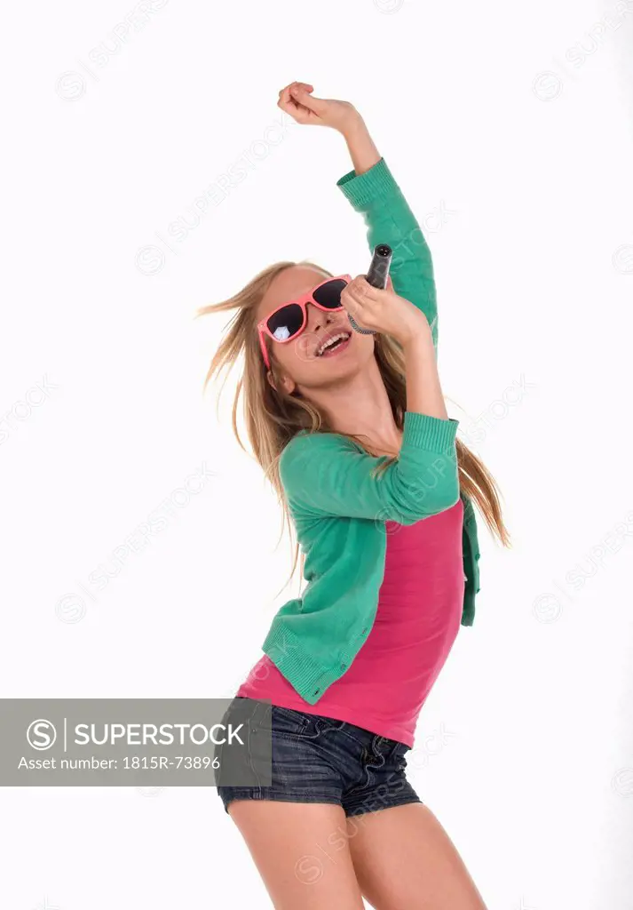 Girl with sunglasses dancing and singing against white background, smiling
