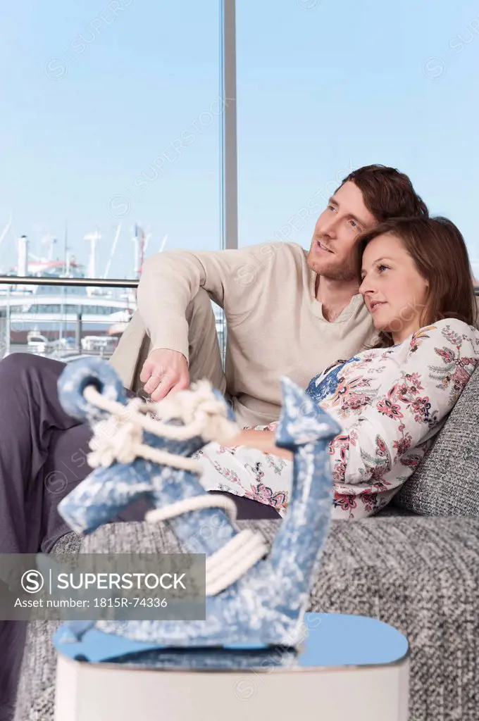 Germany, Hamburg, Man and woman looking away and resting on couch