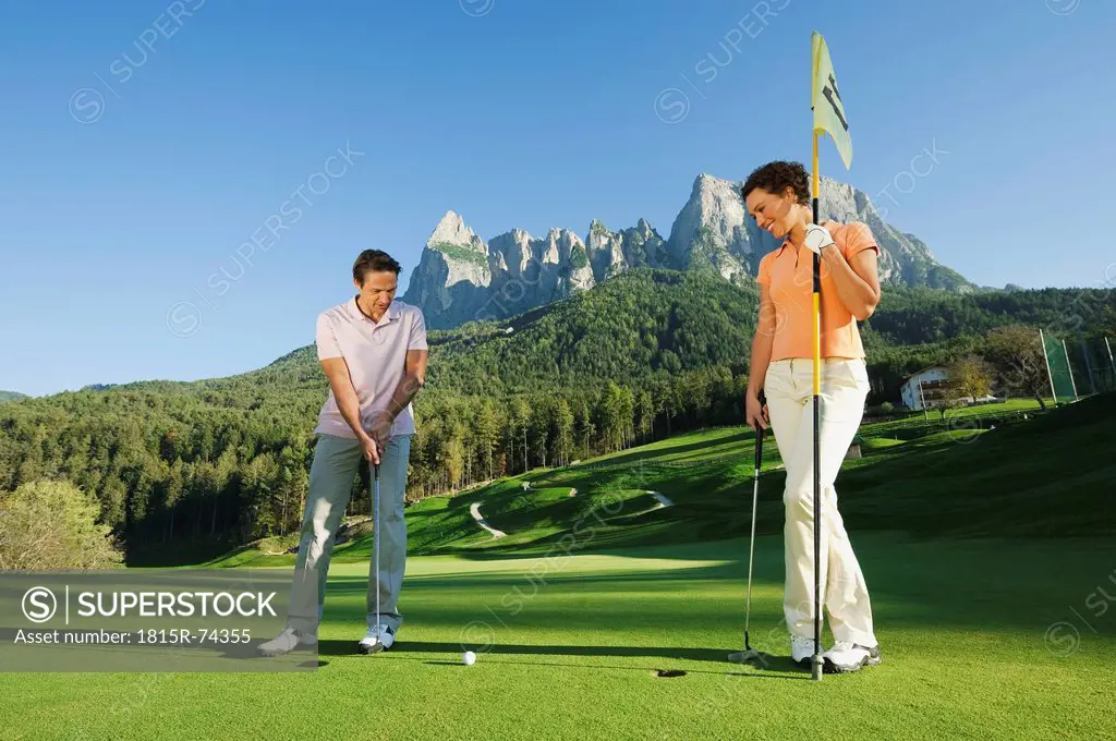 Italy, Kastelruth, Golfers playing golf on golf course