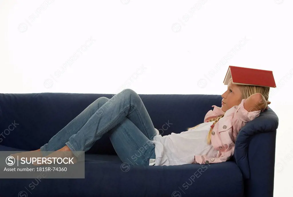 Girl 12_13 Years lying on couch with book on head