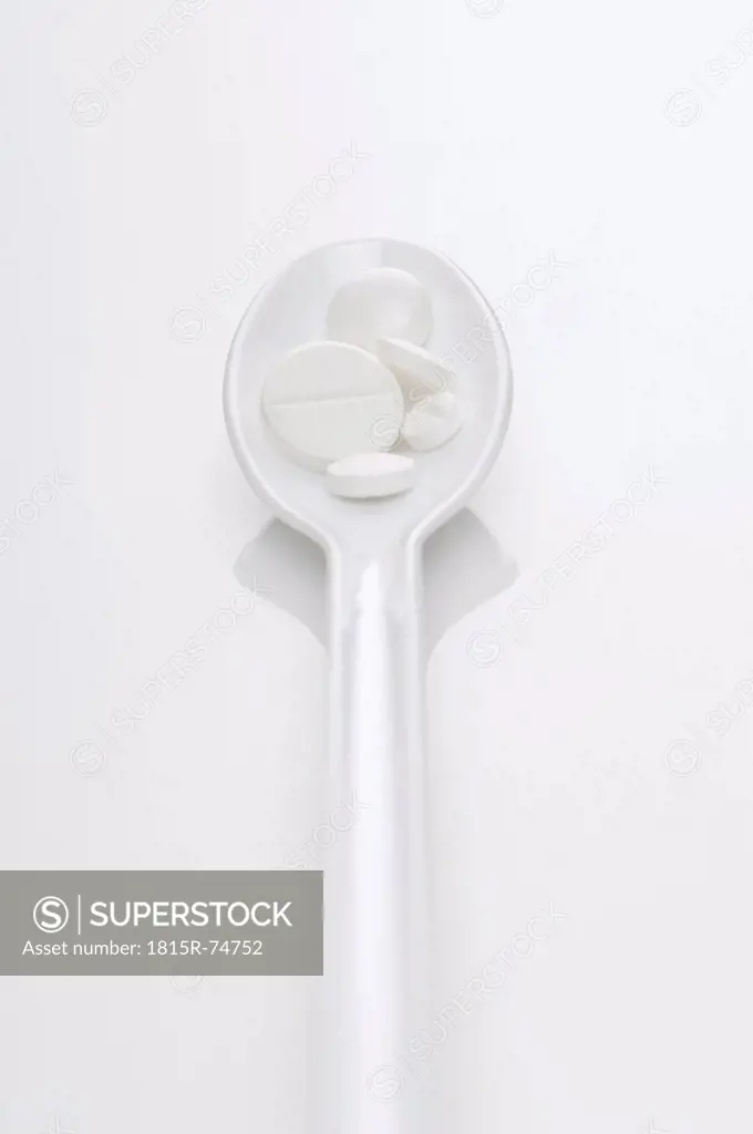Pills in spoon on white background