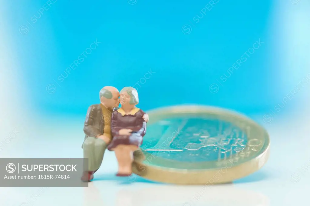 Figurines of senior couple sitting on coin