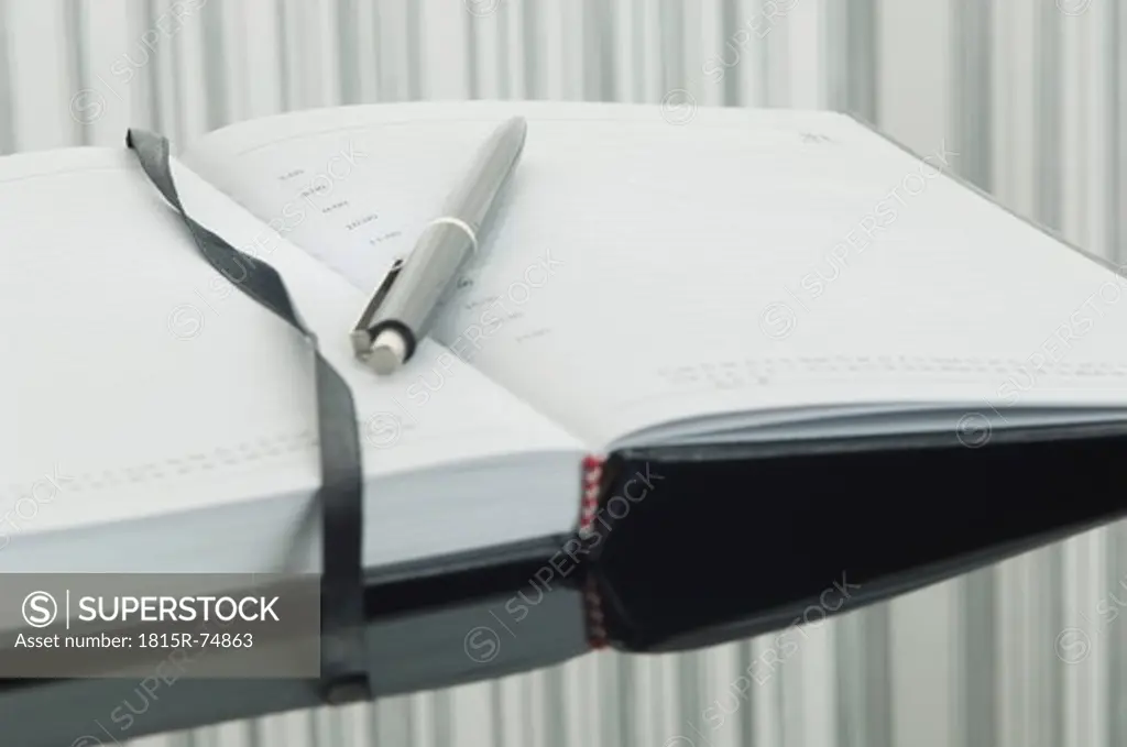Close up of notebook and pen with reflection on table
