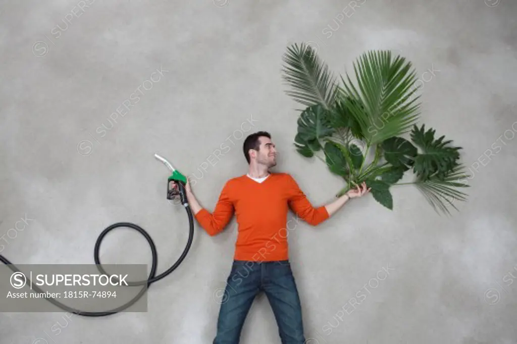 Young man holding industrial hose with plant