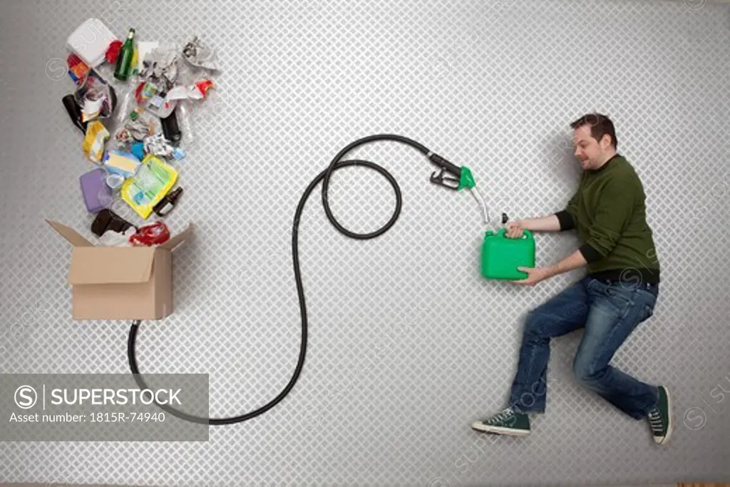 Mid adult man holding petrol can and hose connected to cardboard box