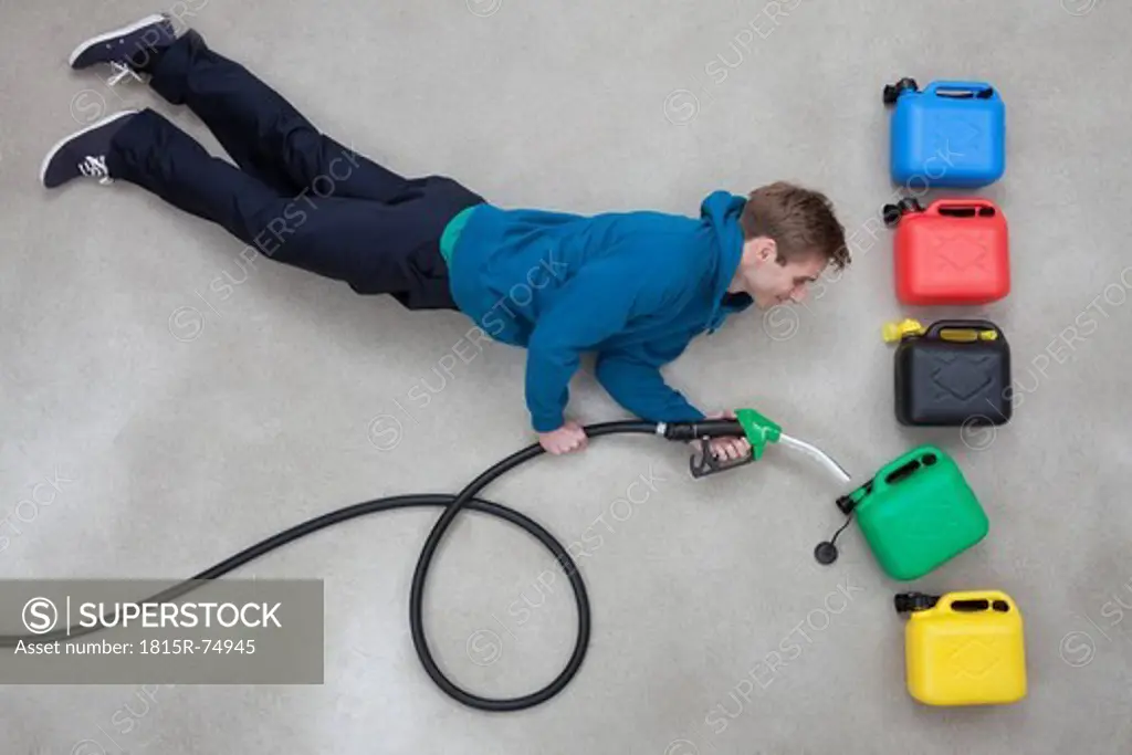 Mid adult man with hose fuelling into green canister