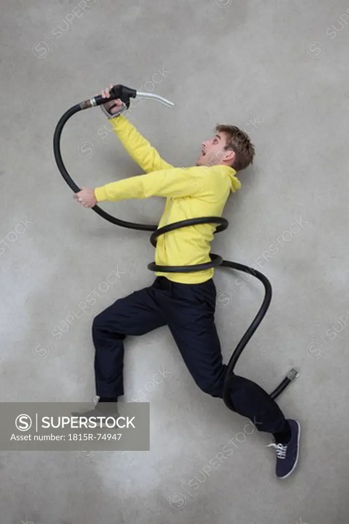 Mid adult man holding and looking shockly at hose