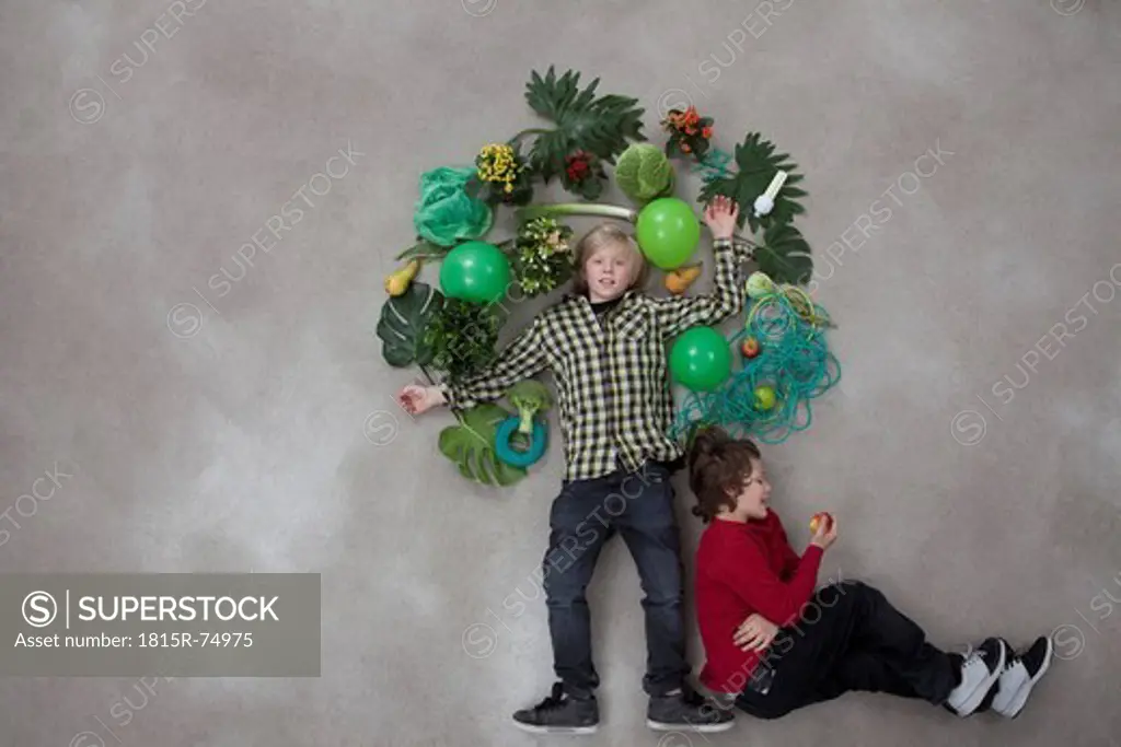 Boy forming tree shape and another boy sitting, eating fruit