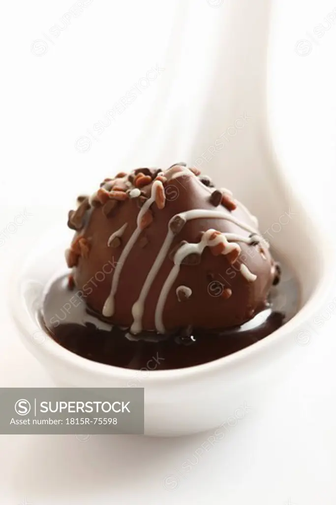 Porcelain spoon with chocolate on white background, close up