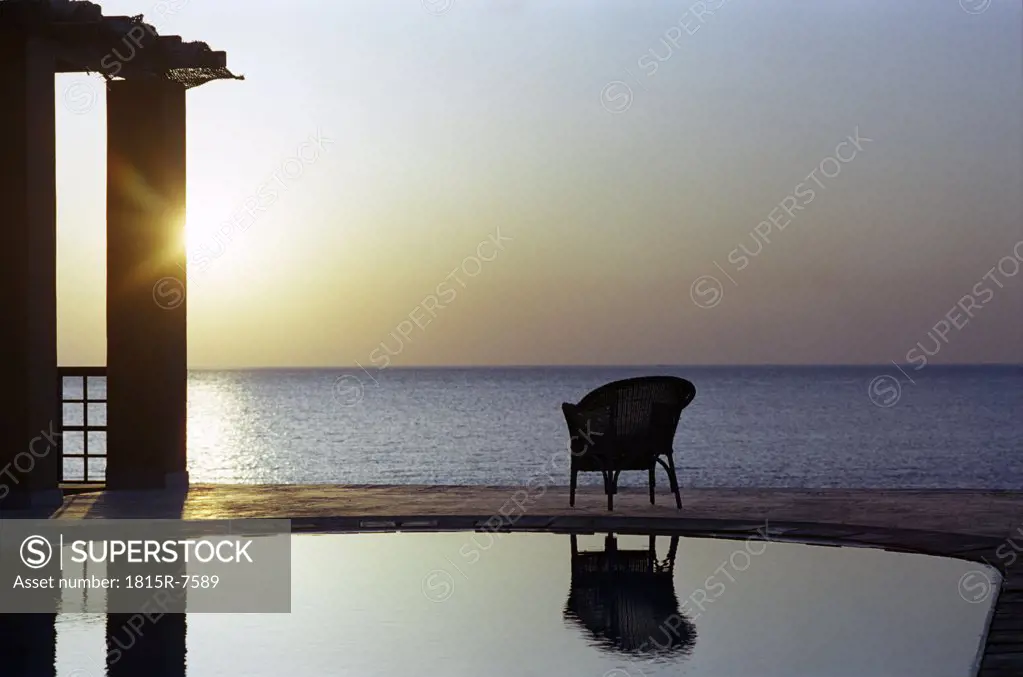 Chair by beach swimming pool, sunset