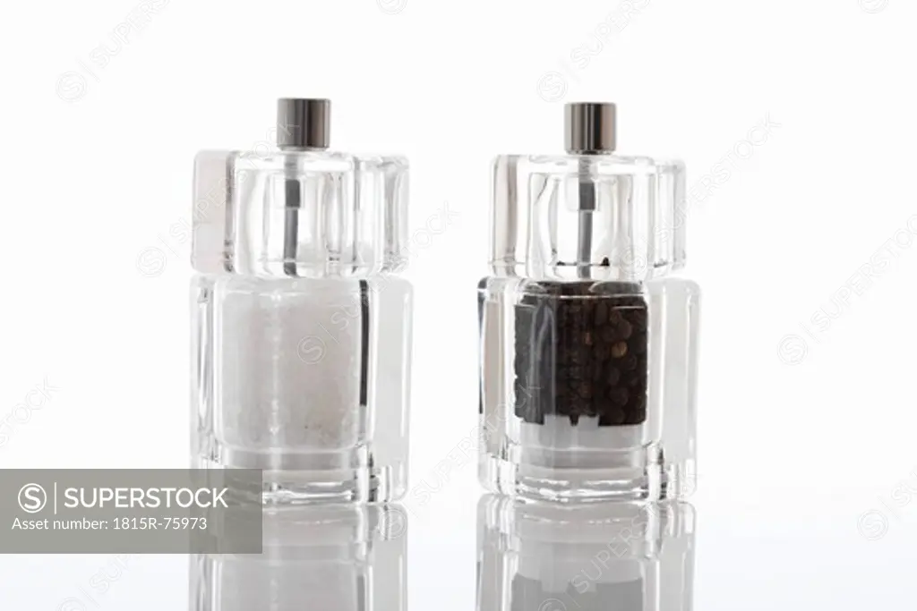 Salt and pepper in spice grinder on white background
