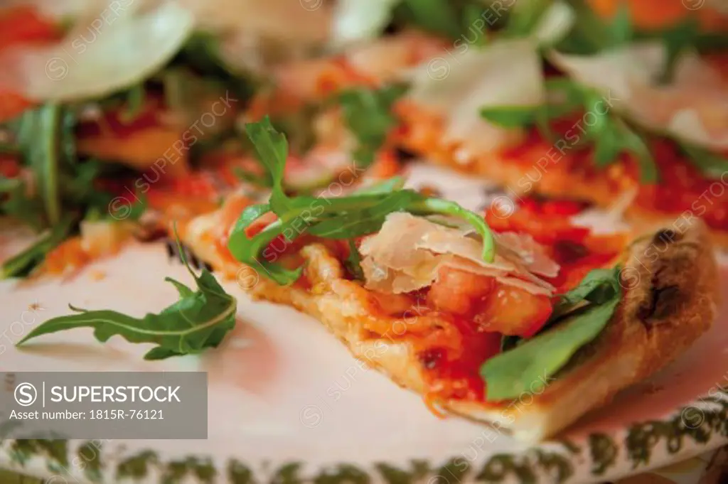 Pizza garnished with rocket, tomatoes and parmesan, close up