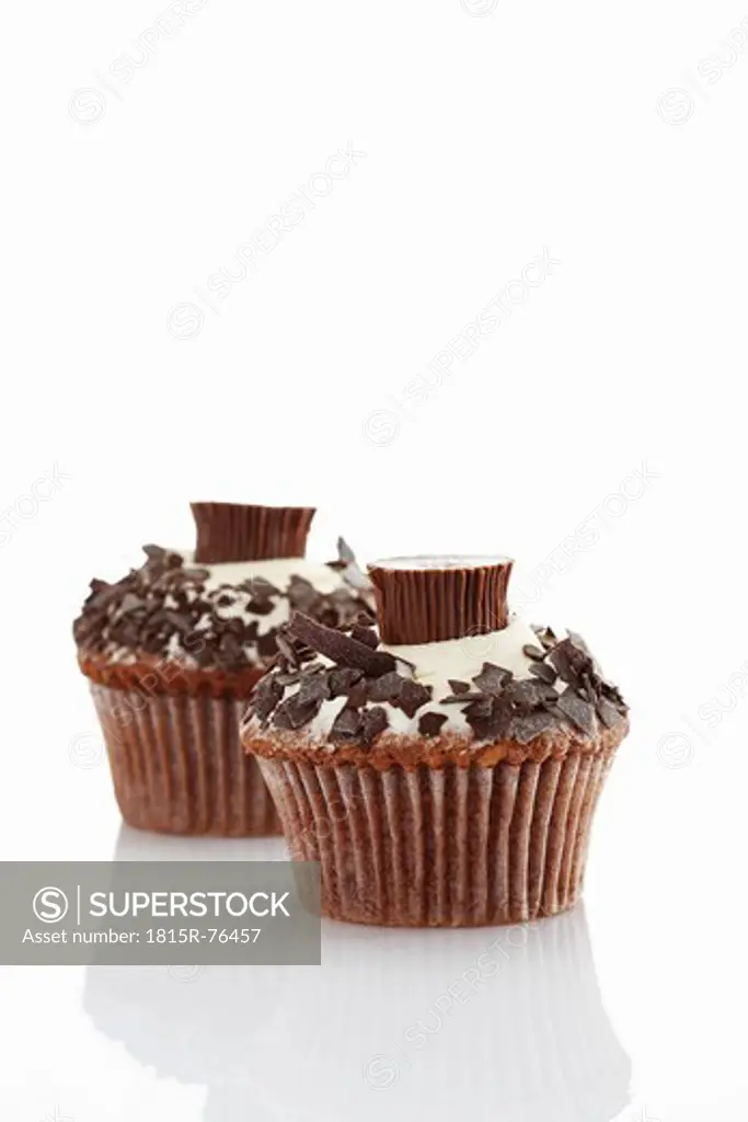 Close up of buttercream cupcake with chocolate crumble and chocolate candy against white background