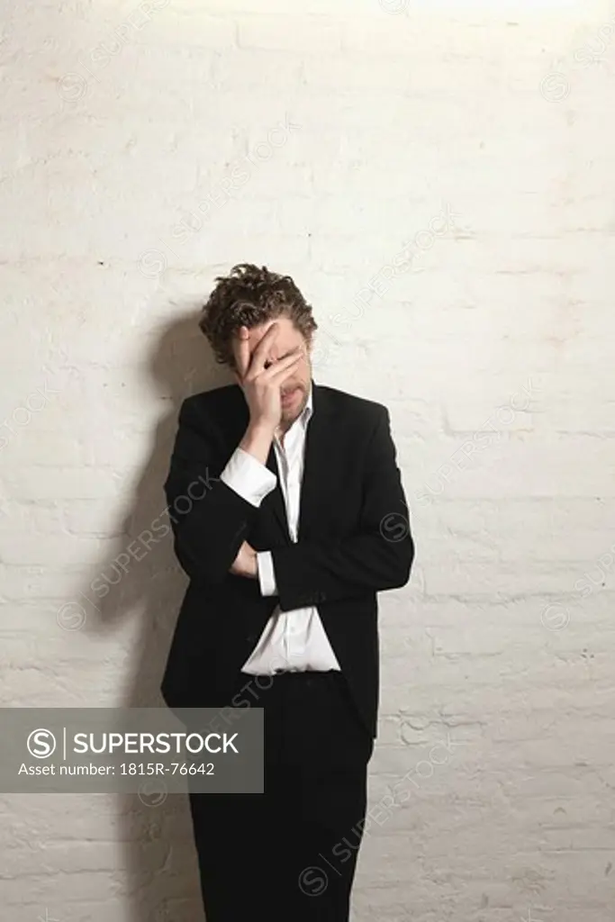 Depressed mid adult man standing against wall