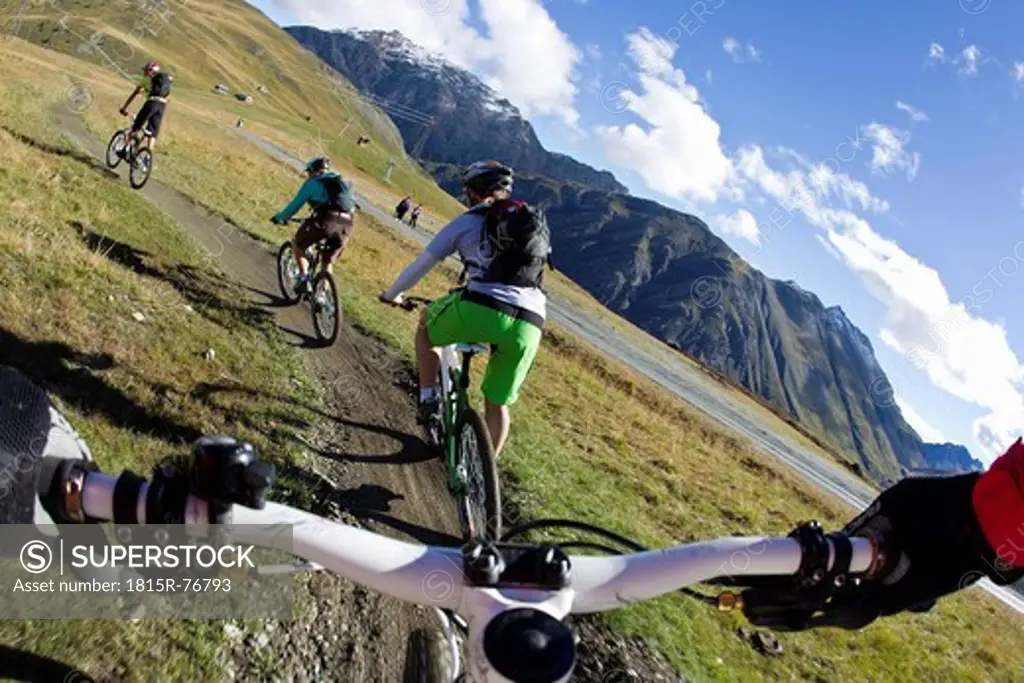Italy, Livigno, View of woman and man riding mountain bike downhill