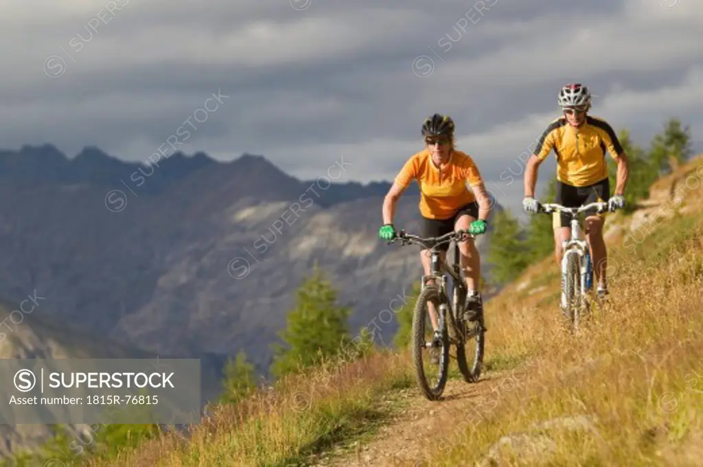 Italy, Livigno, View of man and woman riding mountain bike