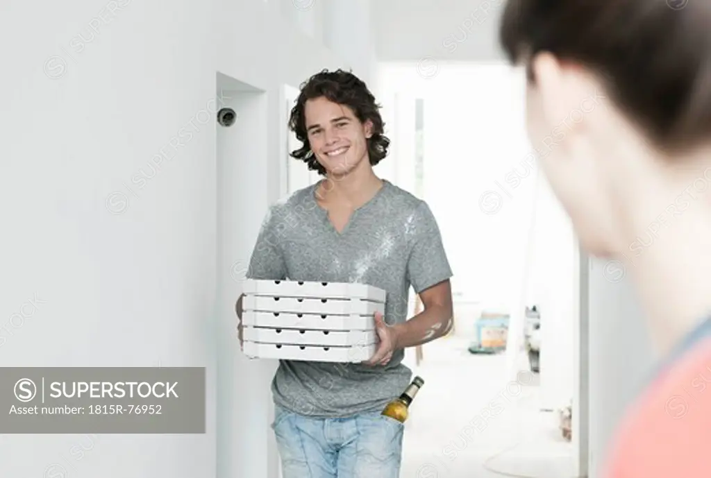 Germany, Cologne, Young man carrying pizza box in renovating apartment