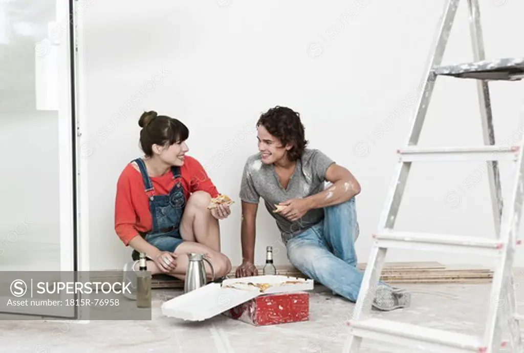 Germany, Cologne, Young couple having lunch break in renovating apartment