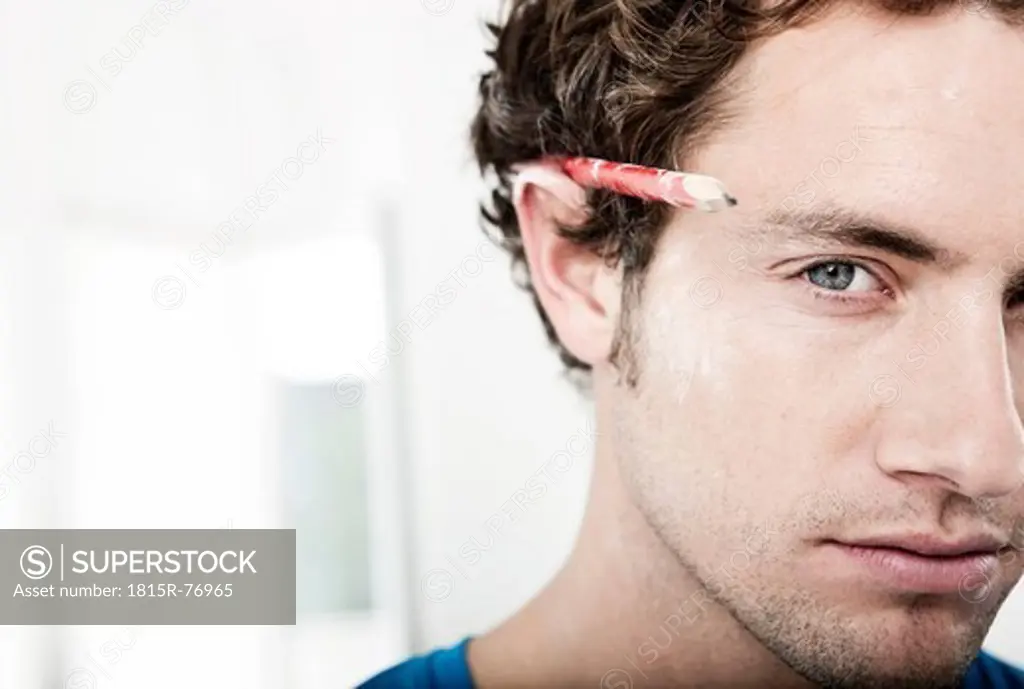 Germany, Cologne, Close up of young man with pencil behind ear in renovating apartment, portrait