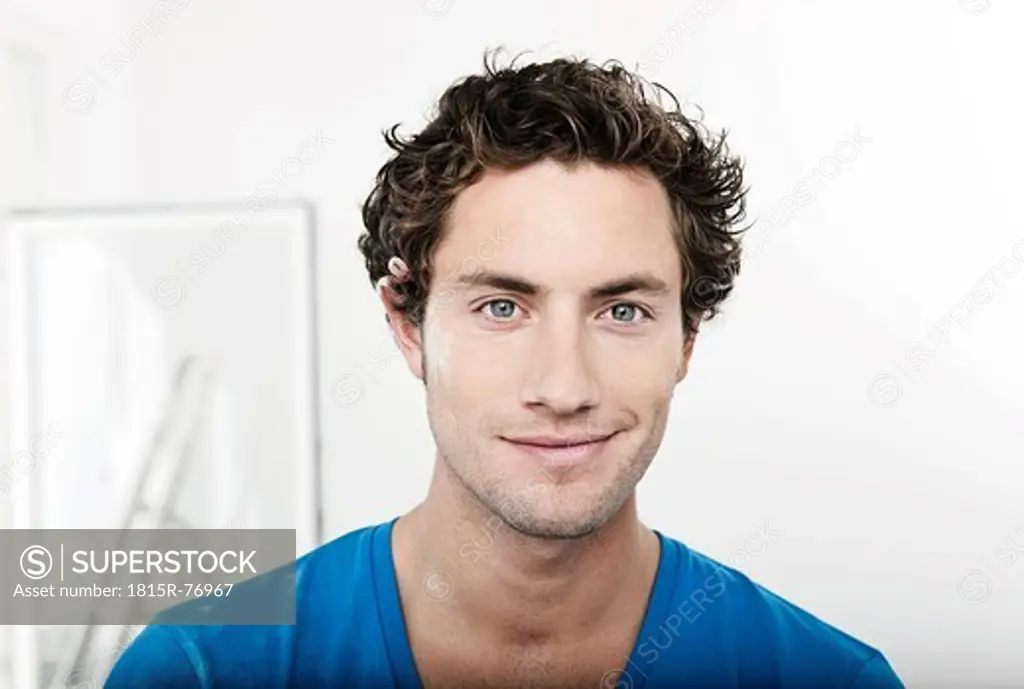 Germany, Cologne, Close up of young man with pencil behind ear in renovating apartment, portrait, smiling