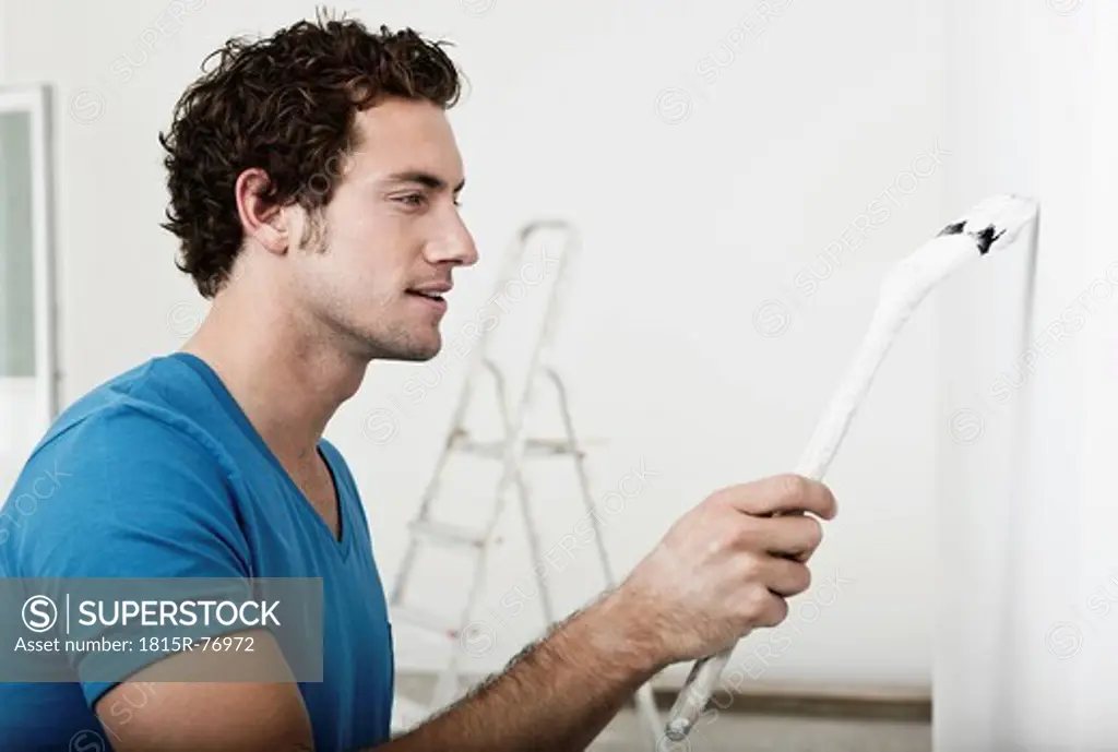 Germany, Cologne, Close up of young man painting in renovating apartment