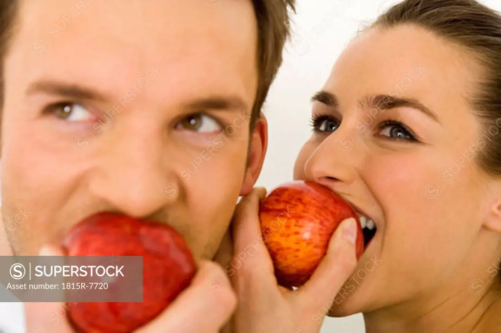 Young couple eating apple, close-up