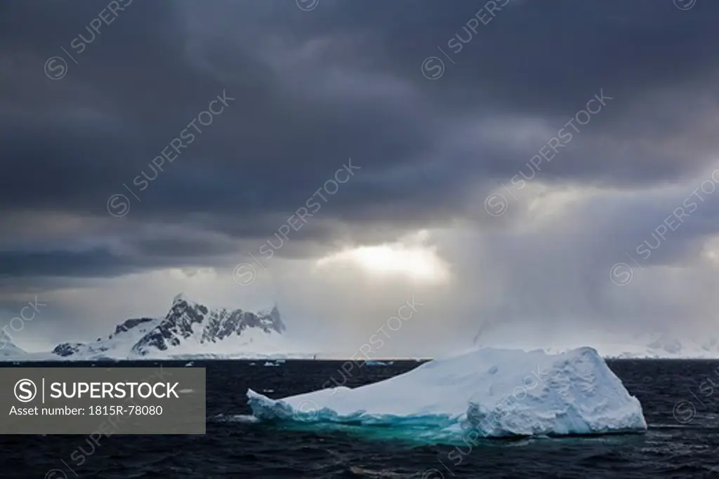 South Atlantic Ocean, Antarctica, Antarctic Peninsula, Gerlache Strait, Iceberg with snow_covered mountain range at dawn