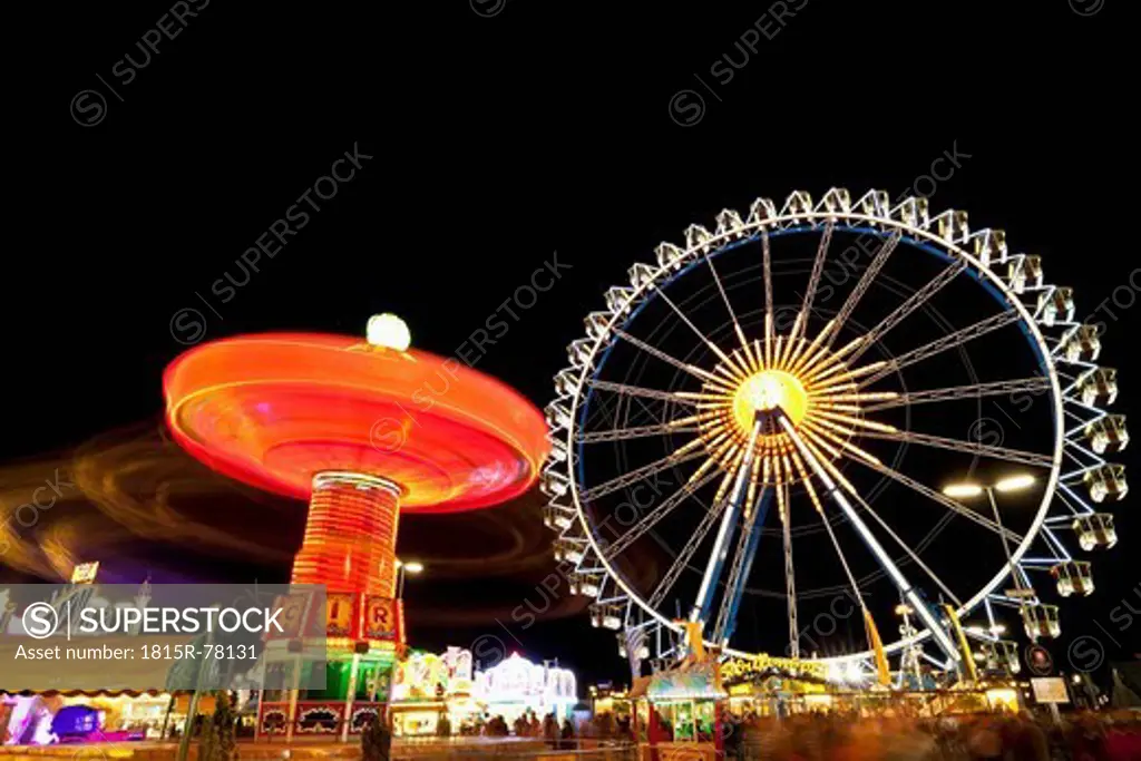 Germany, Bavaria, Munich, View of illuminated chairoplane and ferris wheel at night