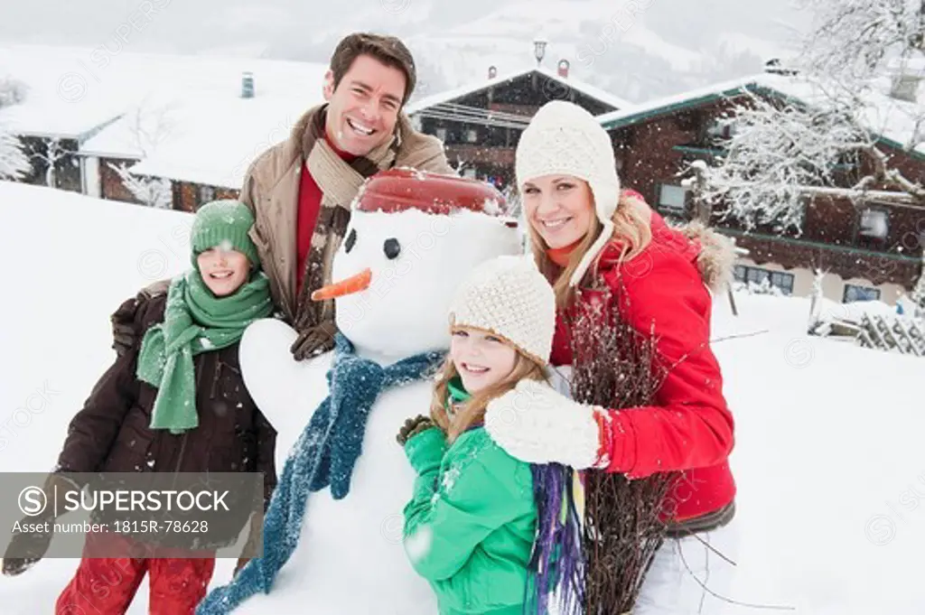 Austria, Salzburg, Hüttau, Family with snowman, smiling