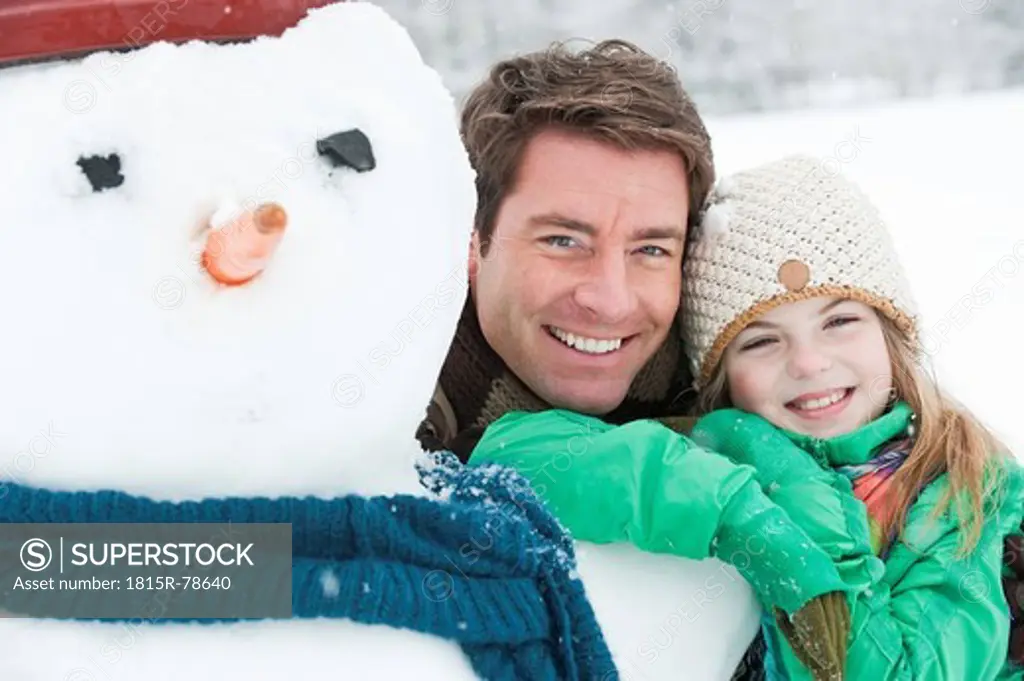 Austria, Salzburg, Hüttau, Father and daughter with snowman, smiling, portrait