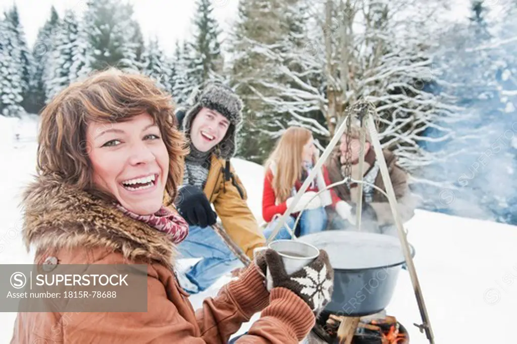 Austria, Salzburg Country, Flachau, Young men and women sitting near fireplace and making tea in snow