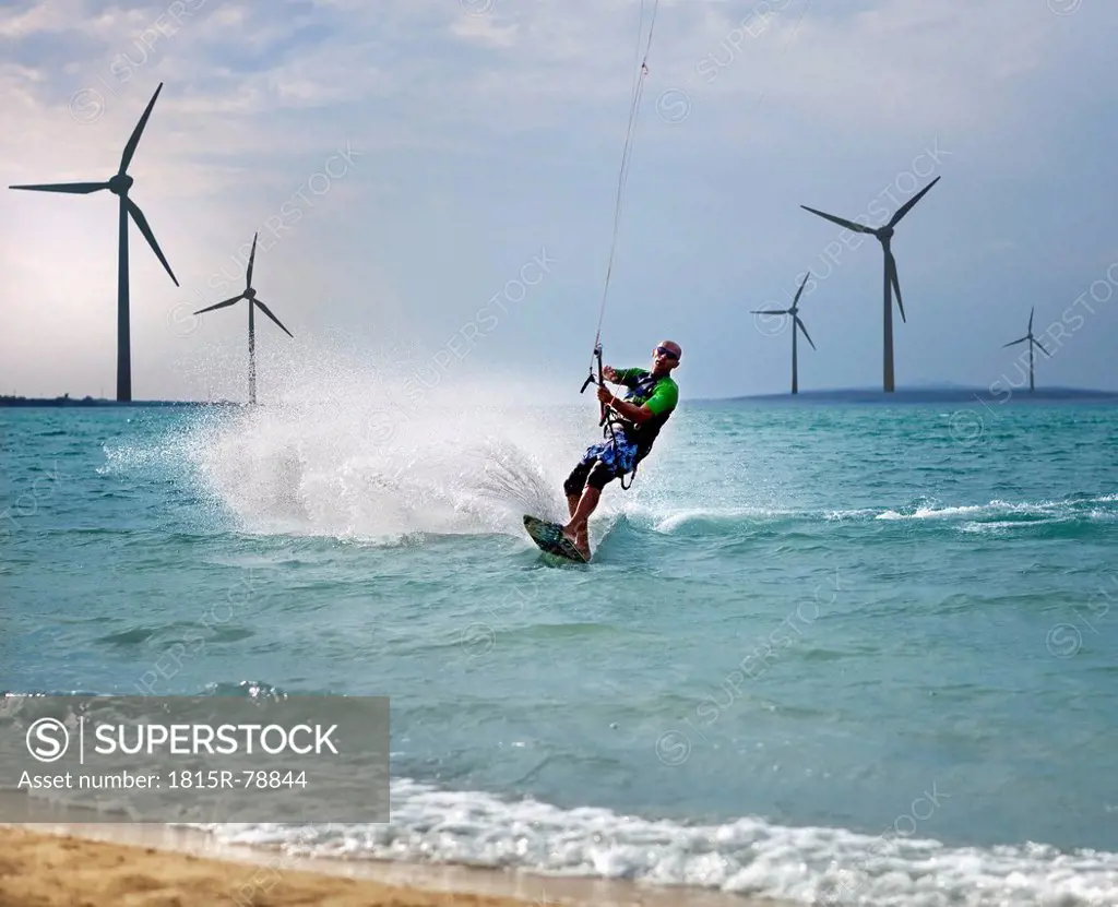 Croatia, Zadar, Kitesurfer jumping in front of wind turbine