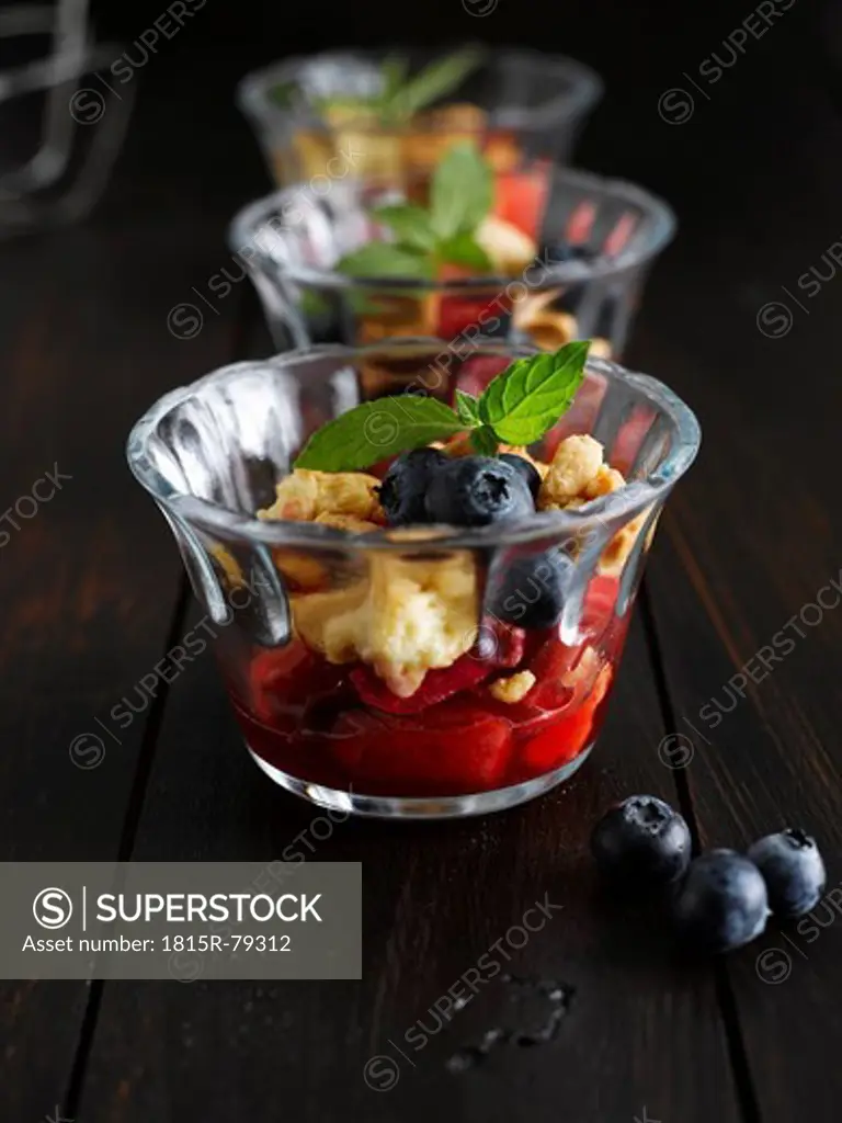 Close up of strawberry crumble with blueberries in glass bowl