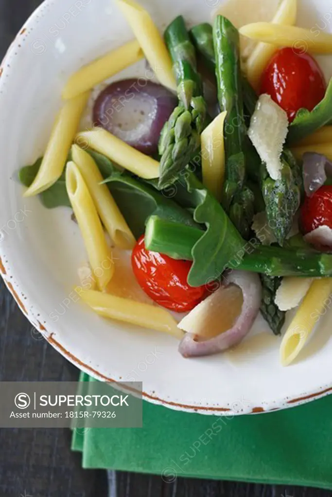 Close up of noodle salad with ruccola, asparagus, parmesan and cherry tomatoes