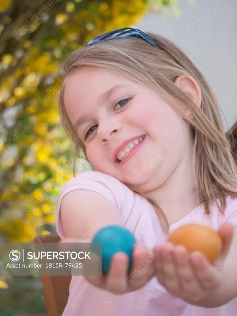 Germany, Bavaria, Close up of girl joking with easter eggs, smiling, portrait